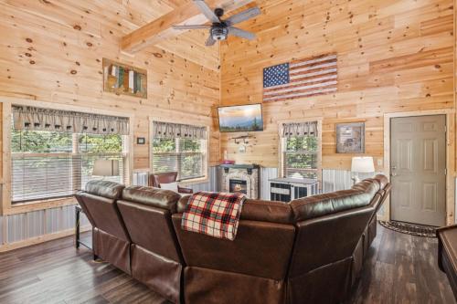 a living room with leather furniture in a log cabin at Falling Brook – Cozy Creekside Cabin with Hot Tub, Game Loft & Dog-Friendly Comfort in Gatlinburg