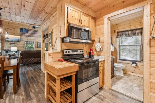 a kitchen with a stove and a table in a cabin at Falling Brook – Cozy Creekside Cabin with Hot Tub, Game Loft & Dog-Friendly Comfort in Gatlinburg