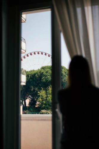 a person looking out a window at a ferris wheel at Hotel Colombo in Lido di Jesolo