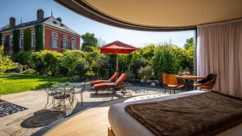 a bedroom with a bed and a patio with a table and chairs at Château de Courban and Spa Nuxe in Courban