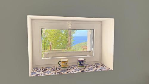 two coffee mugs sitting on a window sill with a view at Casa Flora in Vietri sul Mare