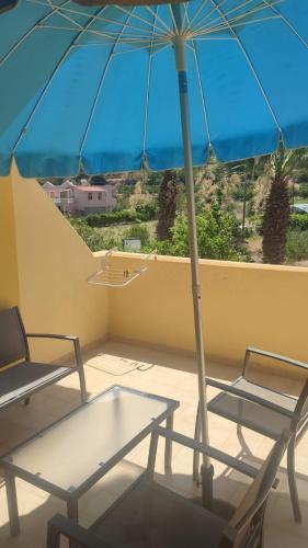 a table and chairs with an umbrella on a balcony at Liros in Kamiros