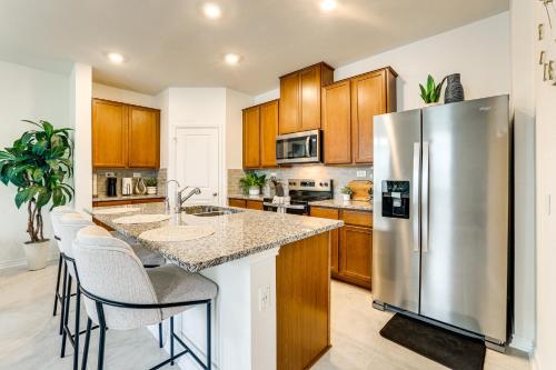 a kitchen with a stainless steel refrigerator and wooden cabinets at 12 Mi to San Antonio River Walk Home with Yard! in Elmendorf