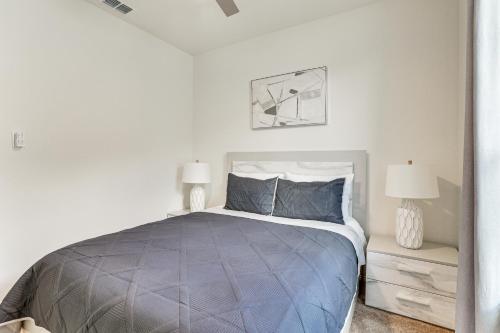 a bedroom with a bed with a blue comforter and two lamps at 12 Mi to San Antonio River Walk Home with Yard! in Elmendorf