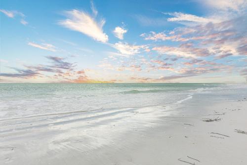 a beach with a cloudy sky and the ocean at Heat of Siesta Village Walk to Beach w heated Pool in Siesta Key