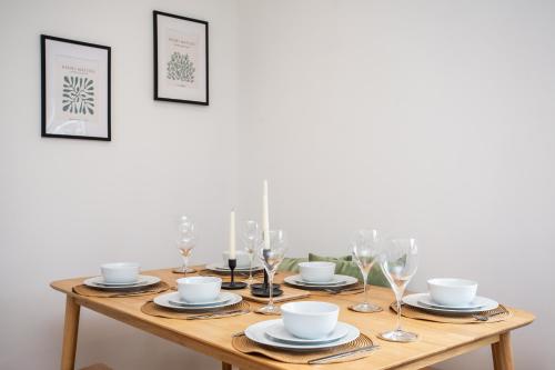 a wooden table with plates and wine glasses on it at Vacant Nest The South End Spacious Smart Tv in Kielder