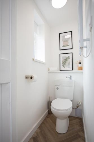 a white bathroom with a toilet and a window at Vacant Nest The South End Spacious Smart Tv in Kielder