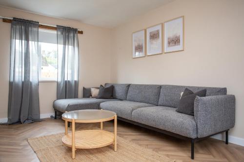 a living room with a gray couch and a table at Vacant Nest The South End Spacious Smart Tv in Kielder
