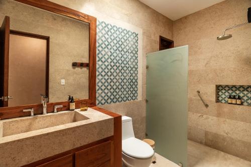 a bathroom with a toilet and a sink and a shower at Villas Caracol in Holbox Island