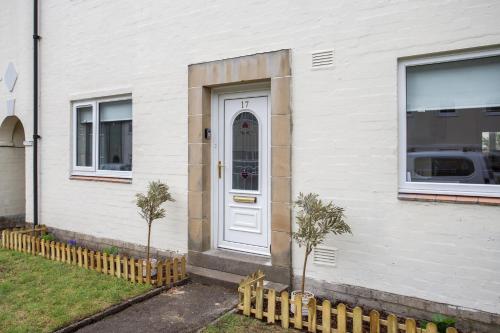 a white house with a white door and two trees at Vacant Nest The South End Spacious Smart Tv in Kielder