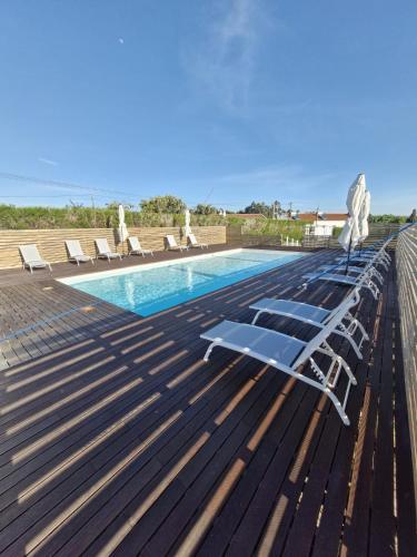 a deck with chairs and a swimming pool at Casa Amarela in Zambujeira do Mar
