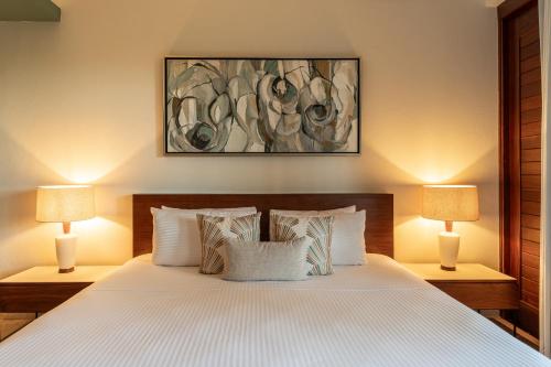 a bedroom with a white bed with two lamps at Villas Caracol in Holbox Island