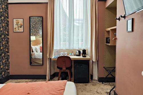 a room with a desk and a bed and a mirror at Hôtel de France, un hôtel AMMI in Nice