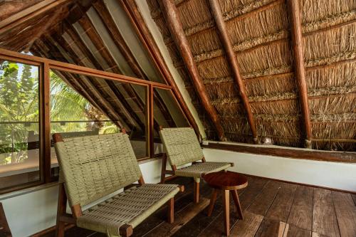 two chairs and a stool in a room with windows at Villas Caracol in Holbox Island