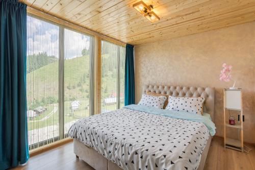 a bedroom with a bed and a large window at NordiKaban A-Frame Vatra Dornei in Ortoaia