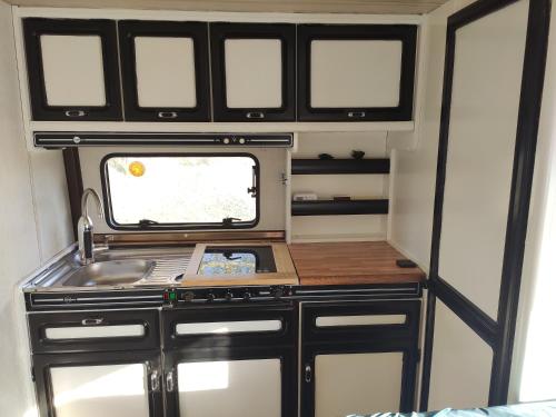 a kitchen in an rv with a sink and windows at Caravane avec spa privatif en campagne in Apremont