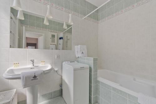 biała łazienka z umywalką i wanną w obiekcie Imperial Apartments - Galeria w mieście Sopot