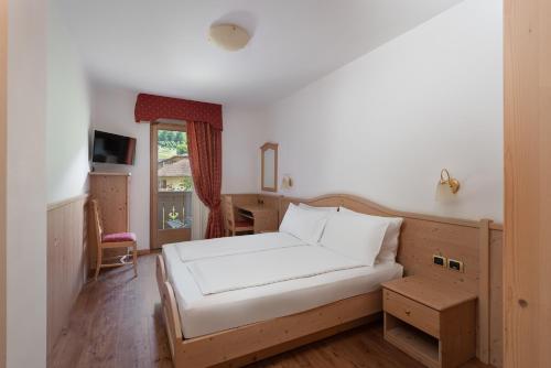a bedroom with a bed and a desk and a window at Beverly Alps Hotel & Spa in Pinzolo