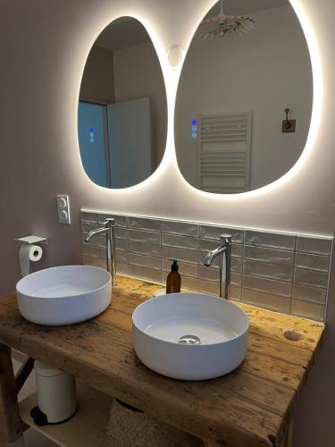 two white sinks in a bathroom with two mirrors at La petite Maison Mima in Le Champ-sur-Layon