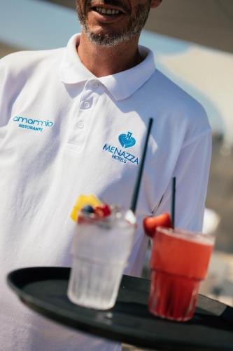 a man holding a tray with two drinks on it at Hotel Colombo in Lido di Jesolo