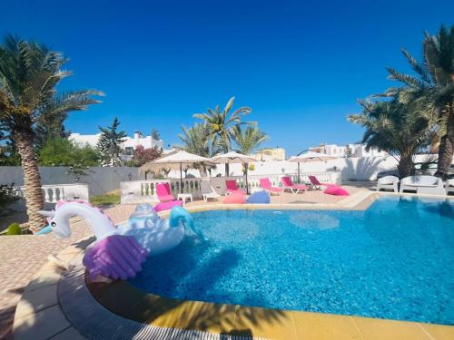 a swimming pool with a swan in the water at Dream Garden Djerba in Djerba