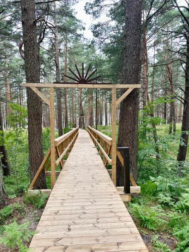 a wooden bridge in the middle of a forest at Villa Gāles Hotel in Saulkrasti