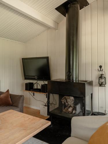 a living room with a fireplace and a flat screen tv at Rustik timmerstuga nära Tandådalens anläggningar in Gusjösätern