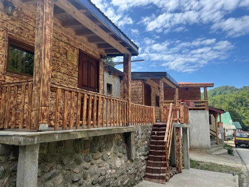 a wooden house with a wooden porch and stairs at Resort Zevs Komovi in Trešnjevik
