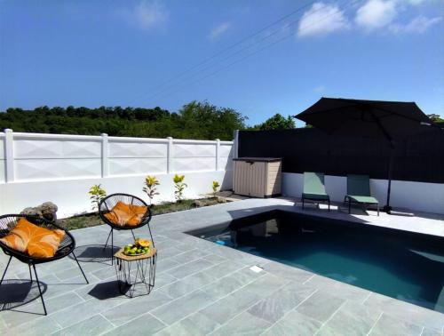 a patio with two chairs and a swimming pool at Villa Citala avec Piscine et Jacuzzi privé in Le Marin