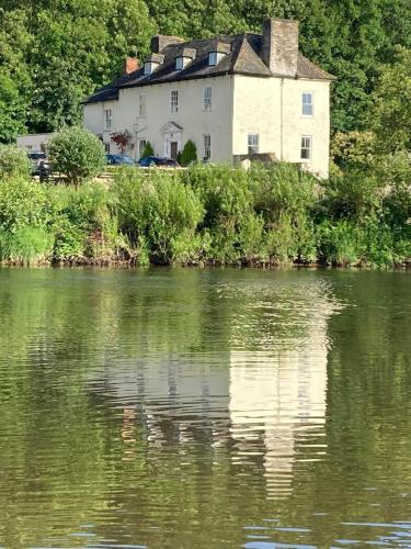 a house sitting on the side of a lake at Aberllynfi Riverside Guest House in Glasbury