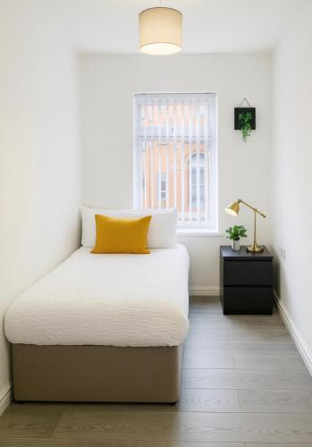 a bedroom with a bed with a yellow pillow on it at Stylish City Getaway Apartment in Dukinfield