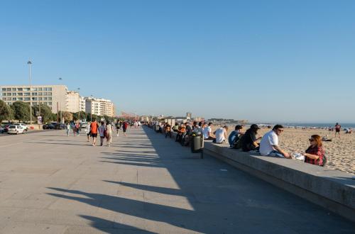 a group of people sitting on a sidewalk near the beach at Trendy Matosinhos Flat by HostWise in Matosinhos