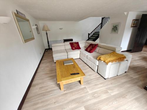 ein Wohnzimmer mit einem weißen Sofa und einem Couchtisch in der Unterkunft Linhay -Farm Cottage in Sidmouth