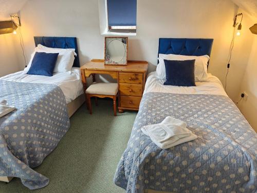 a room with two beds and a desk with a mirror at Linhay -Farm Cottage in Sidmouth