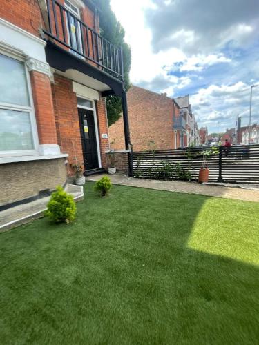 a yard with green grass in front of a house at Modern Double Bedroom with Marble private bathroom in Edgware
