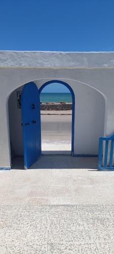 an archway with a blue door on the beach at La Brise de Djerba, Villa de Charme en bord de mer à Al Jazira in Mezraya
