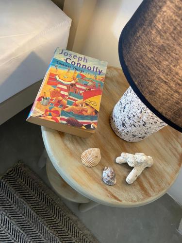 a book and seashells on a table next to a bed at Beachside Stay Steps From Mawella Bay, Tangalle #thisisnotahotel in Mawella