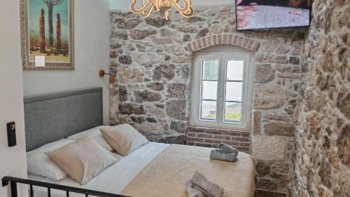 a bedroom with a bed and a stone wall at Sundial Stone House in Ždrelac