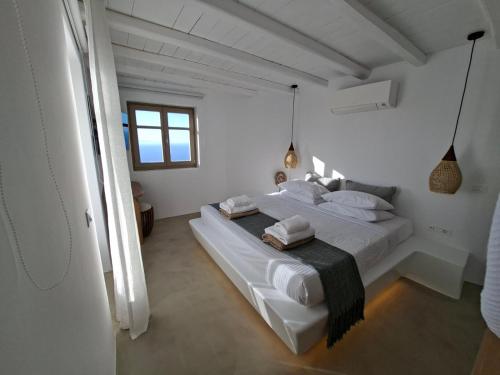 a white bedroom with a bed with white sheets and pillows at ANDELIAS Signature Suites in Chora Folegandros