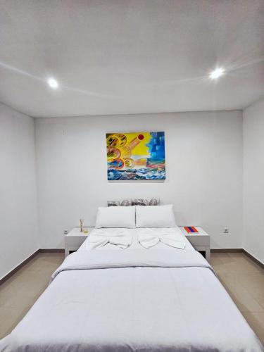 a bedroom with a large white bed with a painting on the wall at Bilene Harmony Home in Vila Praia Do Bilene