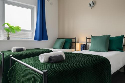 a bedroom with two beds with green sheets and a window at Iron House - Sleeps 11 - For Contractors & Families - Free Parking - Near Excel , Canary Wharf, O2, City AirPort & GreenWich in London