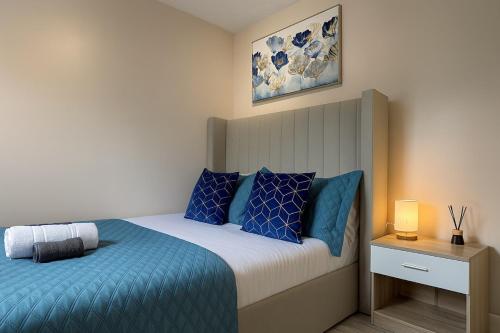 a bedroom with a bed with blue pillows at Iron House - Sleeps 11 - For Contractors & Families - Free Parking - Near Excel , Canary Wharf, O2, City AirPort & GreenWich in London