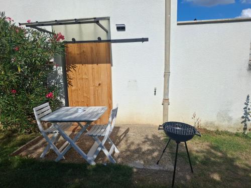 a table and two chairs and a grill in a yard at Charmant studio RDC avec terrasse, parking & cuisine équipée in La Côte-Saint-André