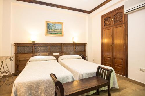 a bedroom with two beds and a wooden cabinet at Hotel América in Granada