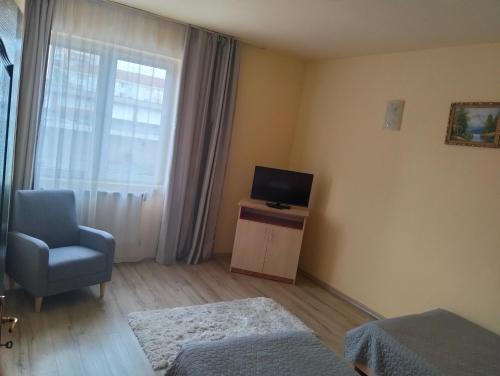 a room with a tv and a chair and a window at Hotel Class in Oradea