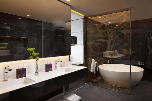 a bathroom with two sinks and a tub and a shower at art'otel London Hoxton in London
