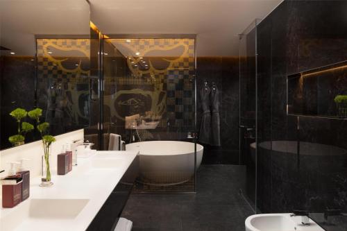 a bathroom with a tub and a toilet and a sink at art'otel London Hoxton in London