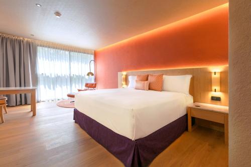 a bedroom with a large bed with an orange wall at Camino Real Polanco Mexico in Mexico City