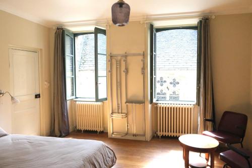 a bedroom with a bed and a chair and two windows at Contes à Rebours - Chambres d'hôtes in Morlaix