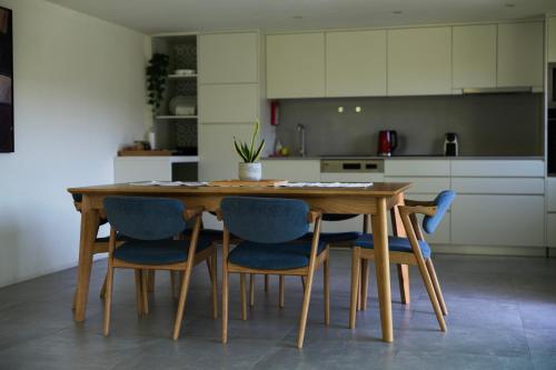 a kitchen with a wooden table and blue chairs at Casas de Pousadouro in Baião